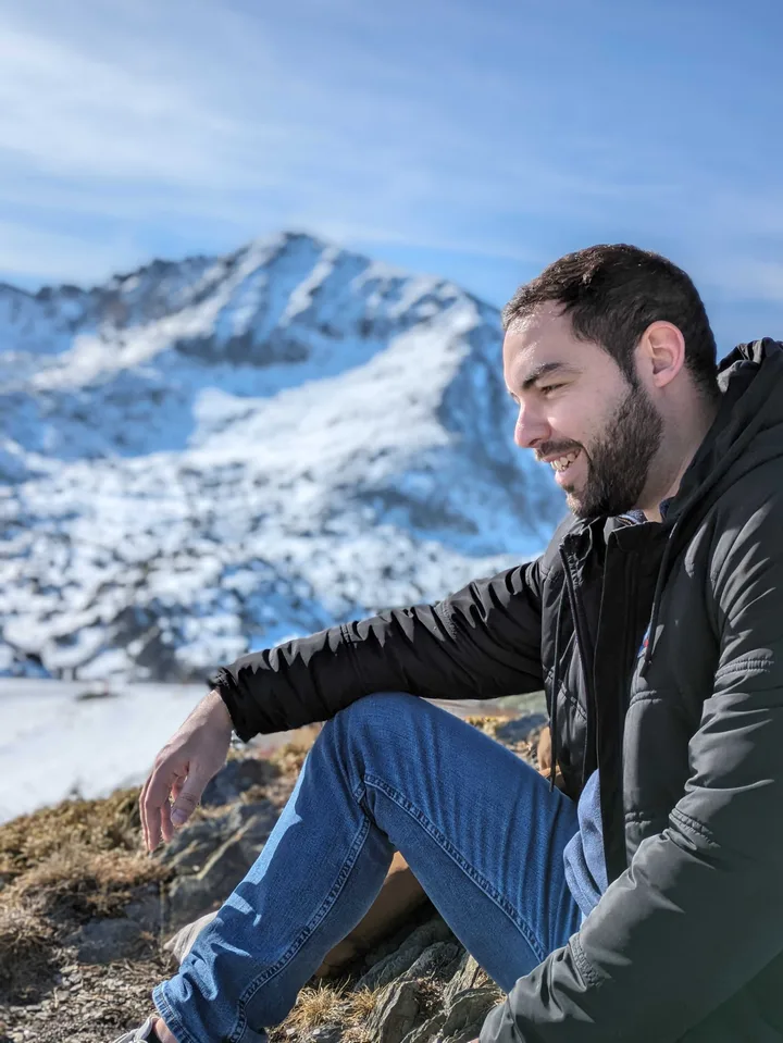 Mathieu sitting outdoors in front of snow-covered mountains